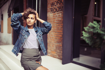 Outdoor close-up photo of smiling cute young woman ienjoying summer against brick wall