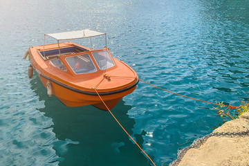  Small orange motor boat in a turquoise sea water, toned