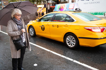 Mature senior white haired woman waiting for taxi cab in New York