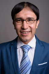 Portrait of young Asian businessman against gray background