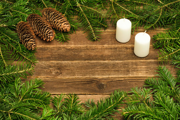 Wooden background with fir branches, cones and candles. Copy space