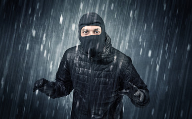 Burglar in action in black clothes with rainy concept. 