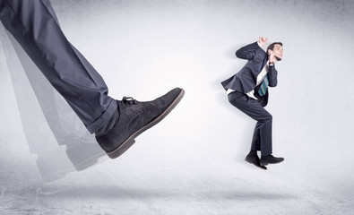 Boss mobbing his worker, illustrated by black shoe kicking small businessman who is flying away in...