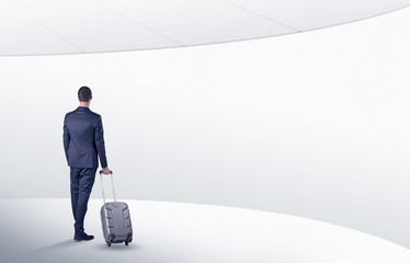 Businessman with back walking in a white waiting room with empty walls around
