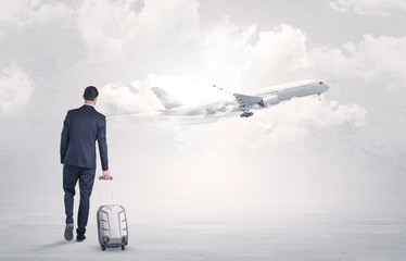 Young businessman with luggage walking towards to a raising airplane
