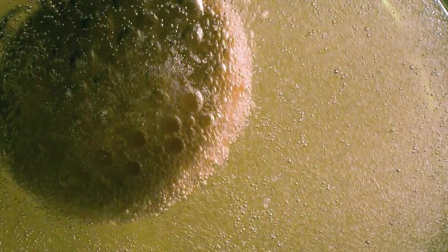 A yellow effervescent tablet against pain falls into a glass and a slow-motion shot of aspirin dissolves on a colored background.