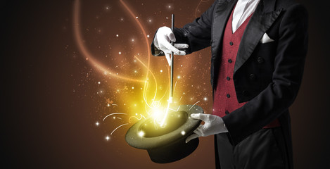 Magician hand conjure with wand  light from a black cylinder