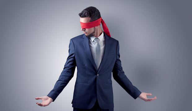 Covered eye, indecisive businessman standing blind in front of a wall