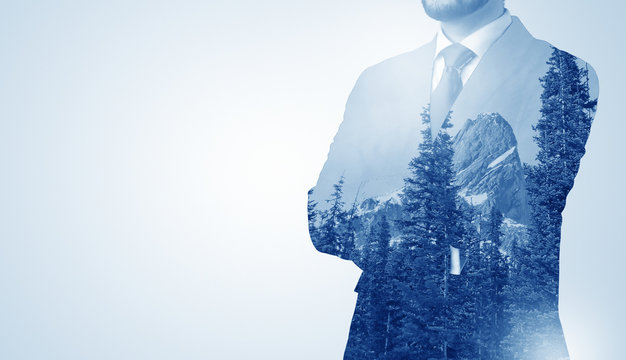 Young businessman standing and meditate with trees on the background 