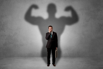 Lovely serious businessman standing with a muscular powerful shadow behind his back
