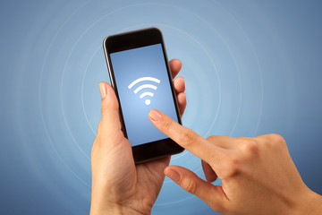 Female fingers touching smartphone with wireless connection icon