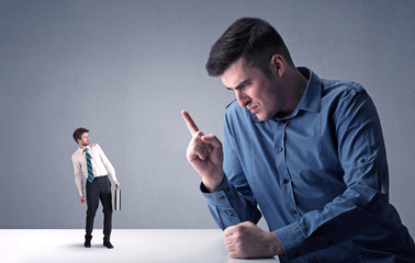 Young professional businessman being angry with an other miniature businessman 