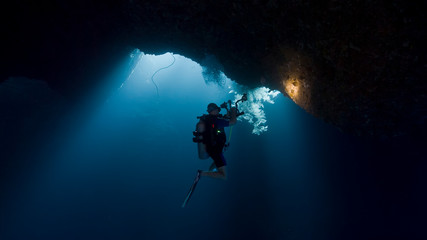 Obraz na płótnie Canvas Scuba divers inside underwater cavern