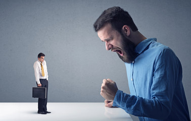 Young professional businessman being angry with an other miniature businessman 