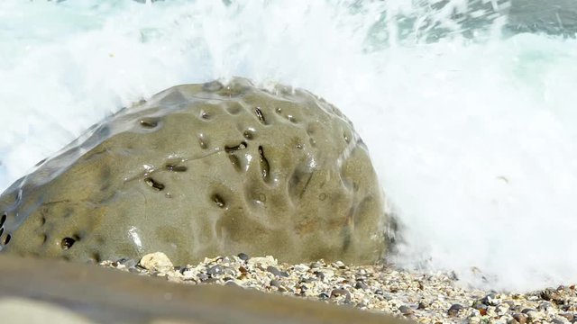 Slow Motion of ocean beach of peebles with the foam of the waves in motion at Taiwan Island. Sea surfs are splashing on multi colored polished stones. The wave on the shore-Dan