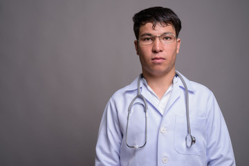 Young Asian man doctor against gray background