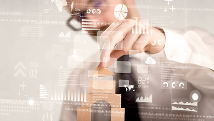 Young handsome businessman using wooden building blocks with mixed data around him