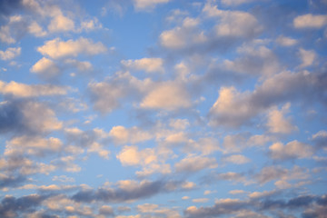 weiße, rosa und graue Wolken in einem herbstlichen Abendhimmel kurz vor Sonnenuntergang