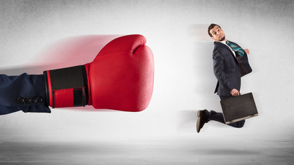 Big red boxing gloves hitting little businessman concept
