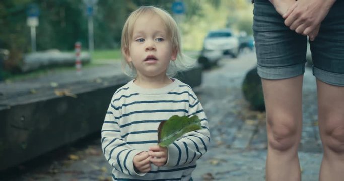 Little toddler standing outside holding a leaf