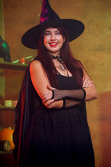 Photo of witch in black dress and hat in magic room