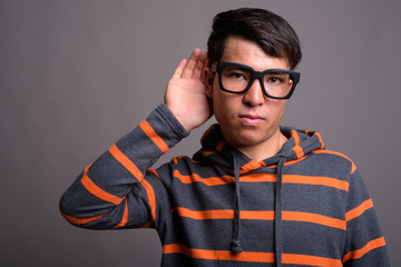 Fototapeta premium Young Asian nerd man wearing hoodie against gray background