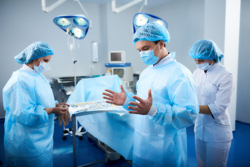 Concentrated professional doctor wearing medical clothes while standing in the operation room before the surgery
