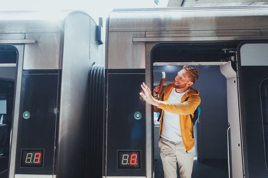 I am leaving. Portrait of handsome red haired gentleman holding passport and ticket while showing goodbye gesture