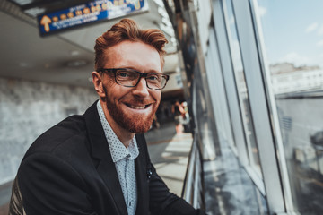 Close up of a smiling adult businessman looking at you while standing at the railway station