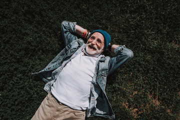 Naklejka premium Top view of happy pensioner spending time on grass and enjoying his life