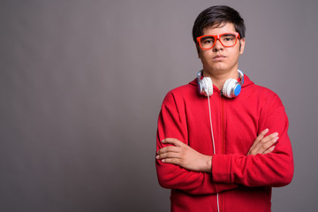 Young Asian teenage boy wearing headphones against gray backgrou