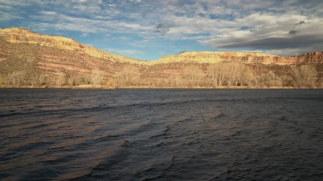 Windy lake in northern Colorado with high sandstone cliff in background - camera panning