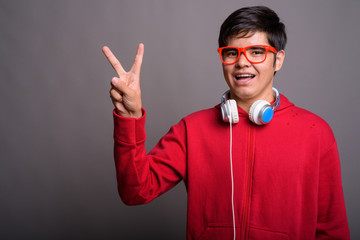 Fototapeta premium Young Asian teenage boy wearing headphones against gray backgrou