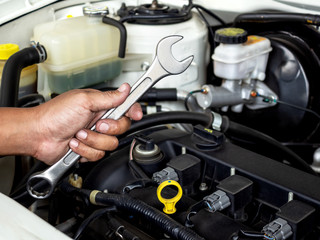 Technician hand holding big wrench for checking, maintenance, repair or changing new part in garage at car auto service.