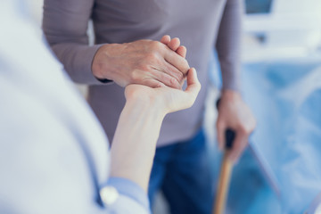Focus on top view close-up of medical worker supporting woman. Patient is using crutch and leaning...