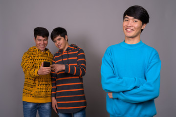 Three young Asian friends together against gray background