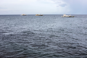Blue grey sea and sky view photo. Rainy day on seaside. White boats in open sea. Rainy season on tropical island