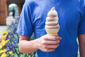 Boy holding a soft serve ice cream cone in the summertime - obrazy, fototapety, plakaty