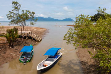 Fototapeta na wymiar Low tide view of boats and a beach in a mangrove forest in Borneo