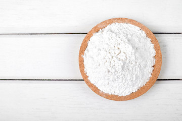 Flour on wooden plate over the white table