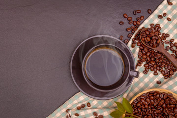 A black coffee in cap with beans and leaves on the black stone with table cloth, for weight loss good health. copy space