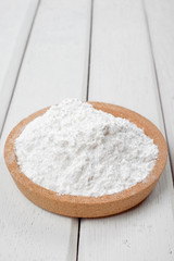 Fototapeta na wymiar Flour on wooden plate over the white table