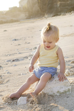 
Candid outdoor portrait of blonde hair baby sitting on the beach, natural backlight photo