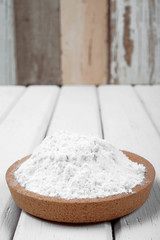 Flour on wooden plate over the white table
