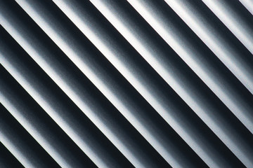 An abstract look at metal blinds with a diagonal tilt, with emphasis on highlights and shadows.