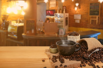 Hot cup of coffee and beans with burlap sack on the wooden table, with copy space