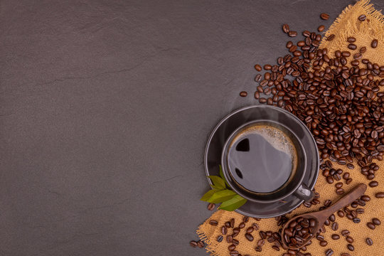 A black coffee in cap with beans and leaves on the black stone with sackcloth, for weight loss good health. copy space
