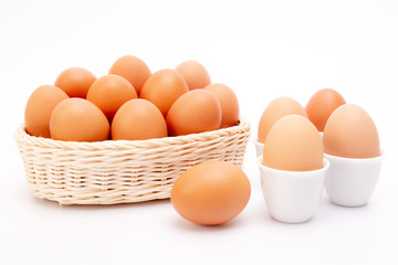 Brown Eggs  in ceramic cup and basket at White Background