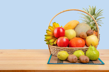 Composition with assorted fruits in wicker basket on wooden table, balanced diet, copy space