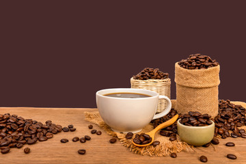 Hot cup of coffee  and beans with burlap sack on the wooden table, with copy space